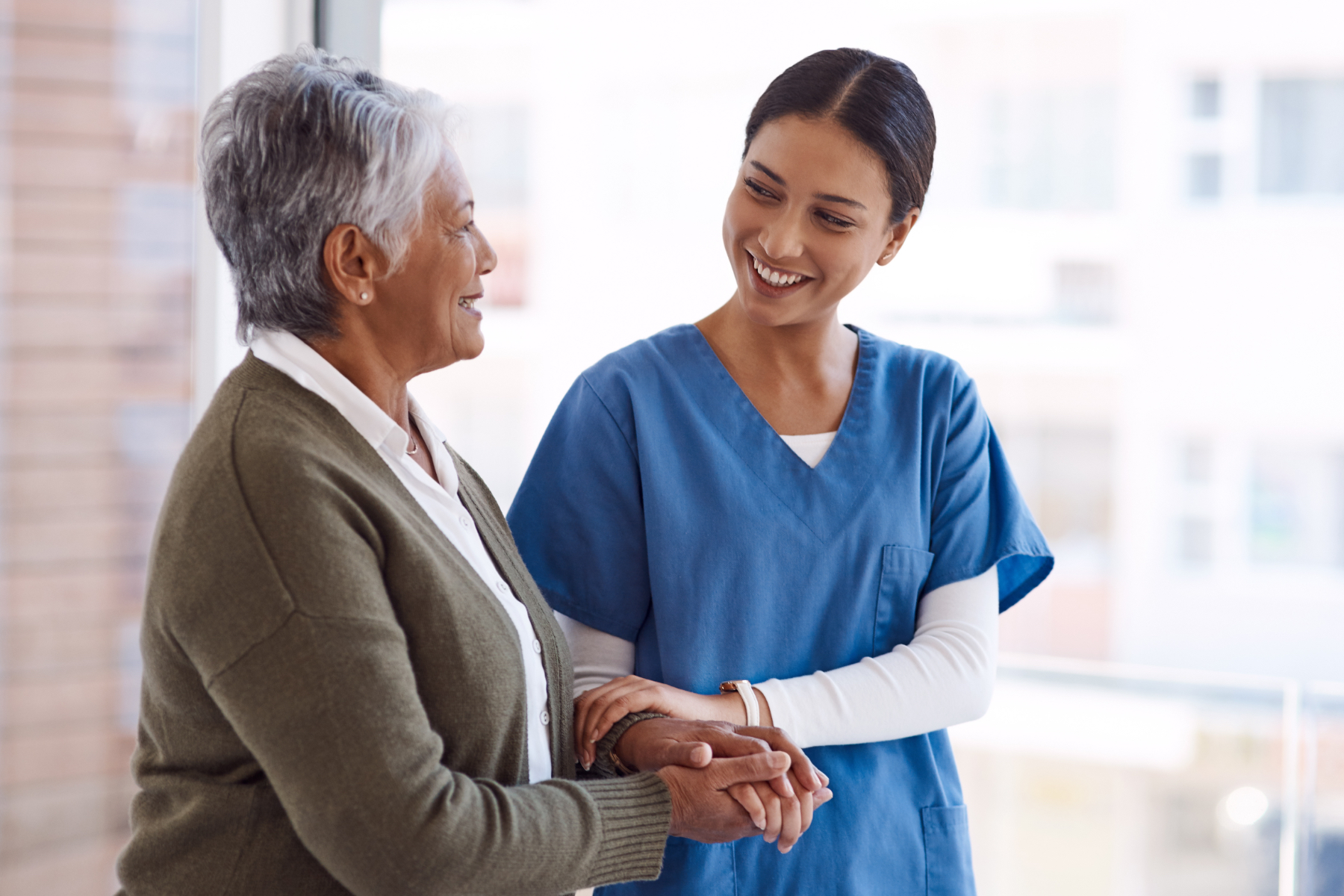 Image of a nurse smiling at a patient and holding her hands