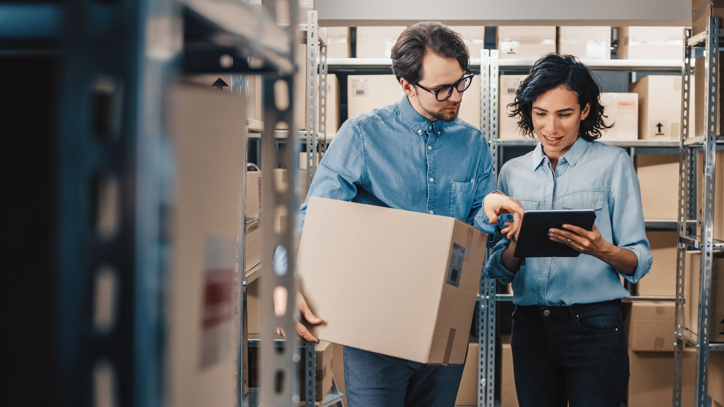 Image of two people looking at a tablet inside a storage area