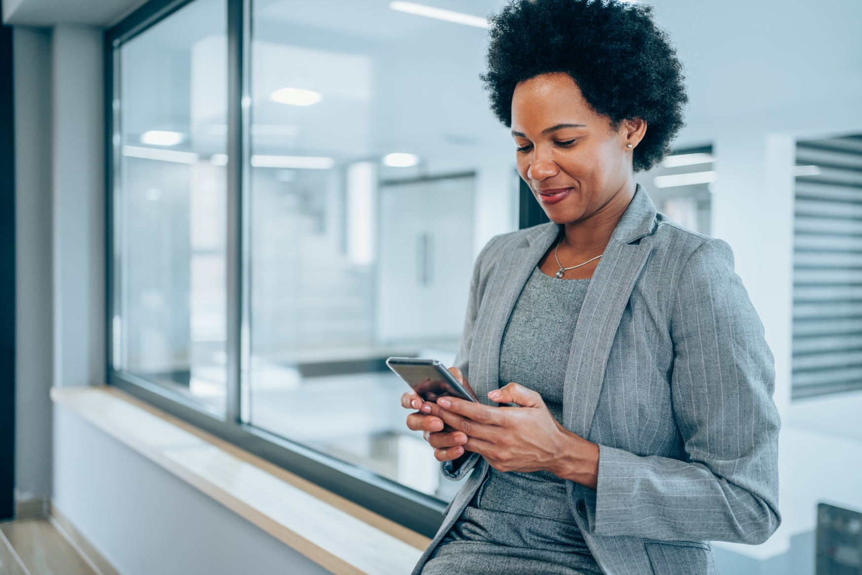 Woman in hallway smiling at smartphone