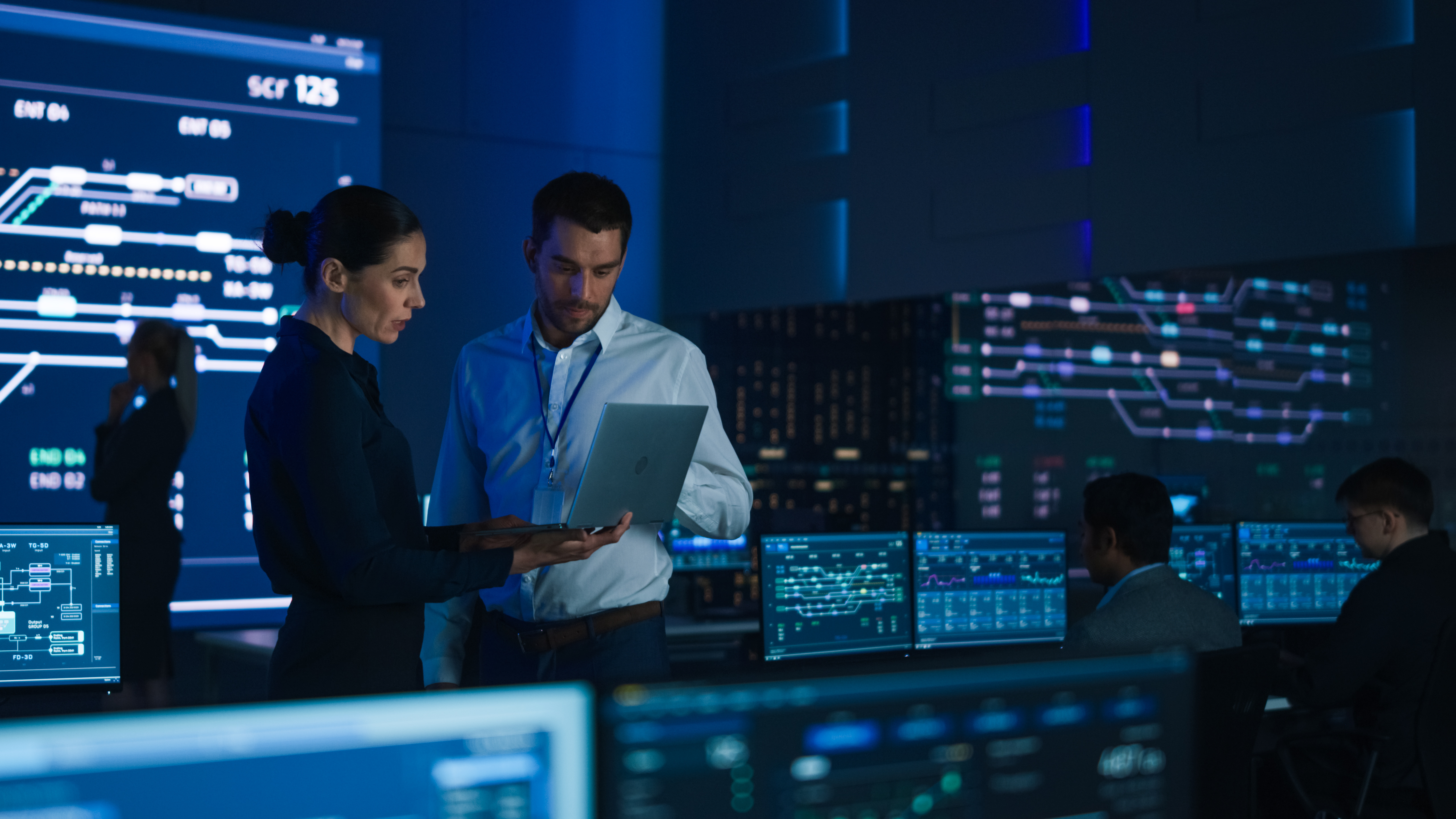 Two people viewing a device inside a server room