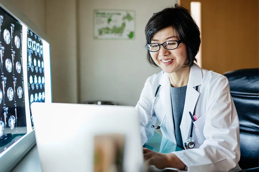 A smiling doctor using a laptop